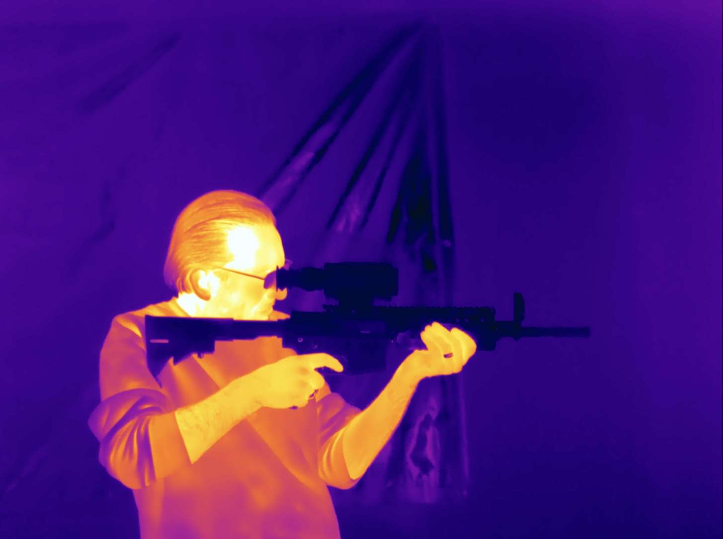 man looking through thermal scope while being looked at with thermal