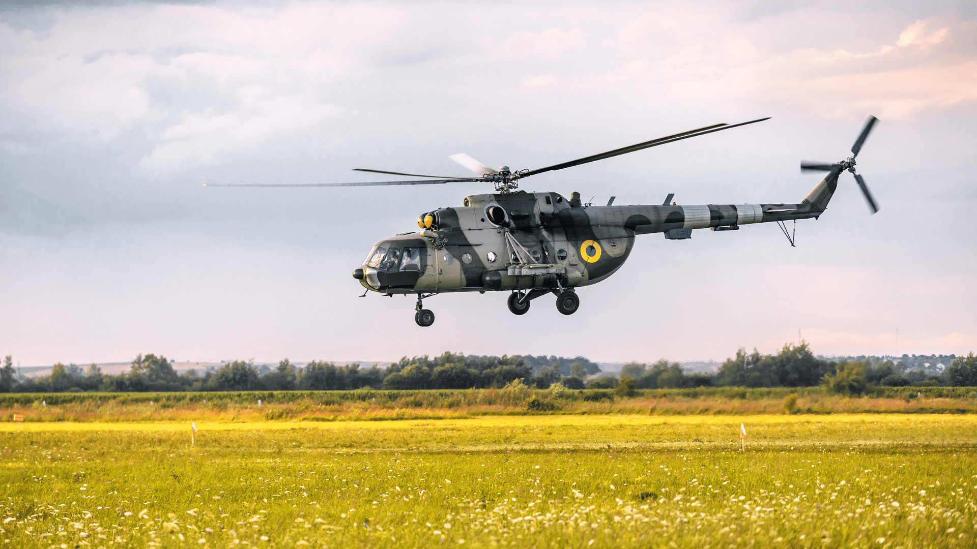 military helicopter flying over field