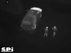 aerial thermal image of 2 soldiers standing by a car